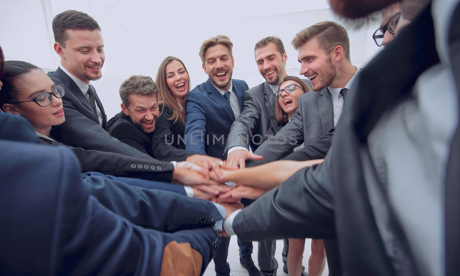 concept of team building. large group of business people standing with folded hands together