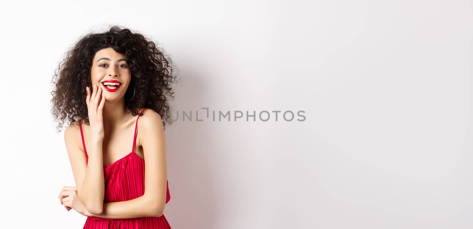 Attractive woman in party dress, laughing and having fun, smiling happy at camera, wearing makeup red lipstick, standing on white background by Benzoix