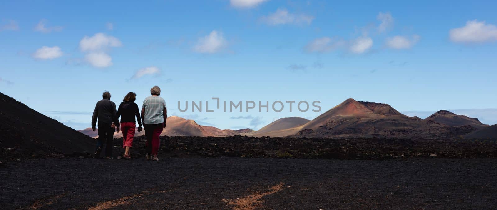 Tourists visiting volcanic landscape of Timanfaya National Park in Lanzarote. Popular touristic attraction in Lanzarote island, Canary Islands, Spain. by kasto