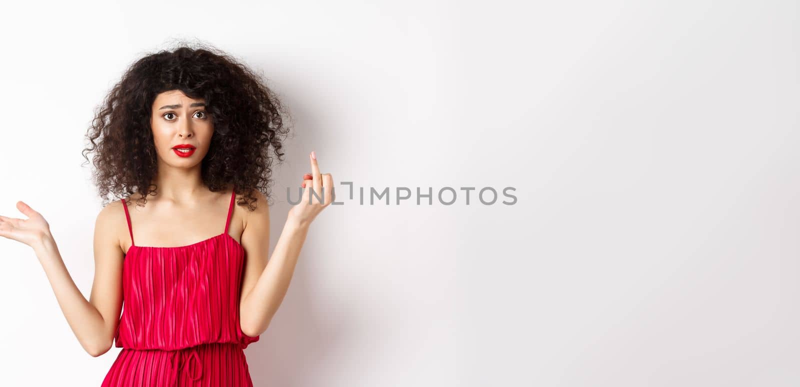 Annoyed caucasian woman in red dress, showing finger without wedding ring, arguing about marriage, standing pissed-off on white background.