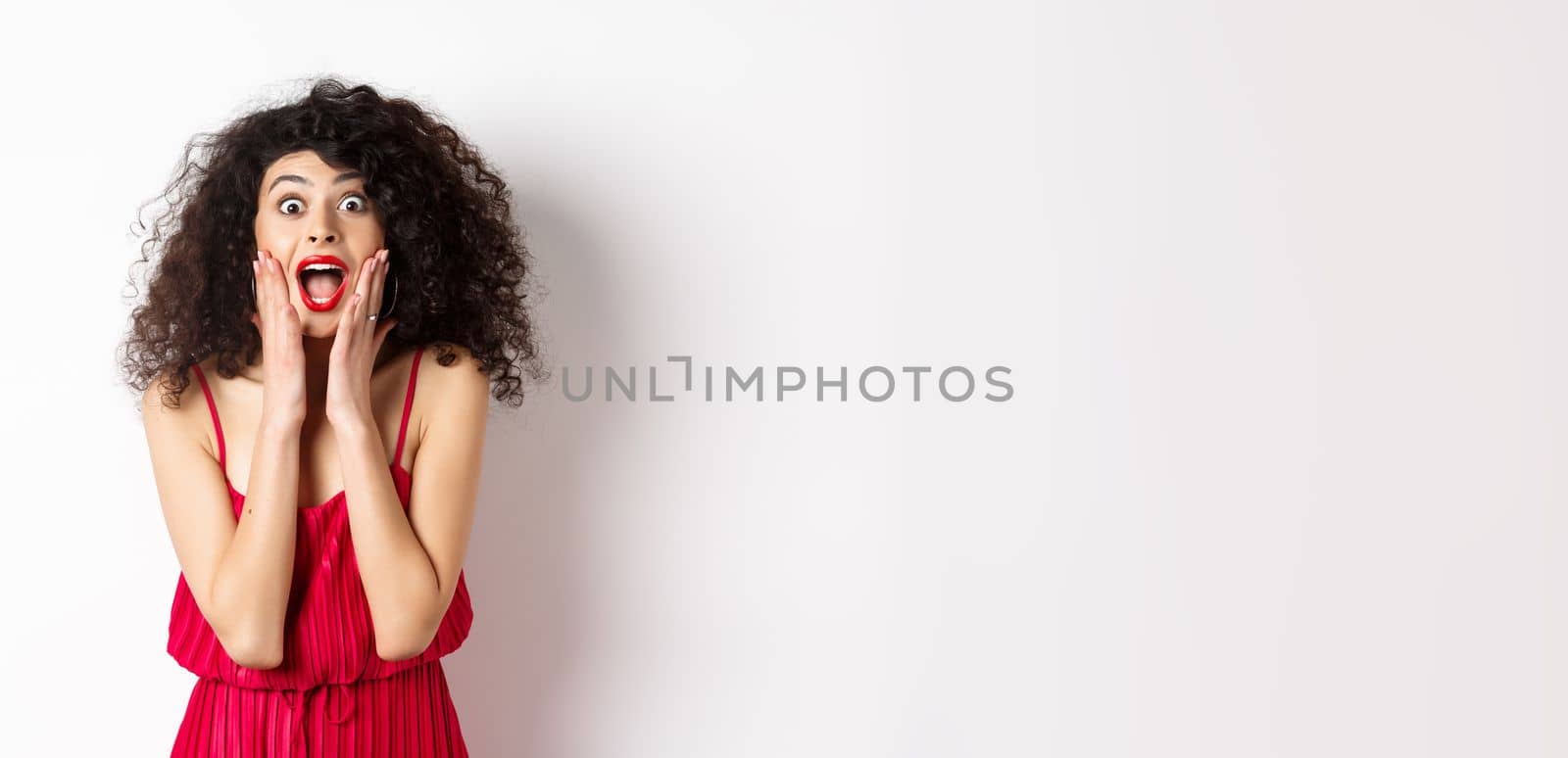 Image of elegant woman scream surprised, staring at camera, see promo offer and shouting of joy, standing in dress over white background by Benzoix