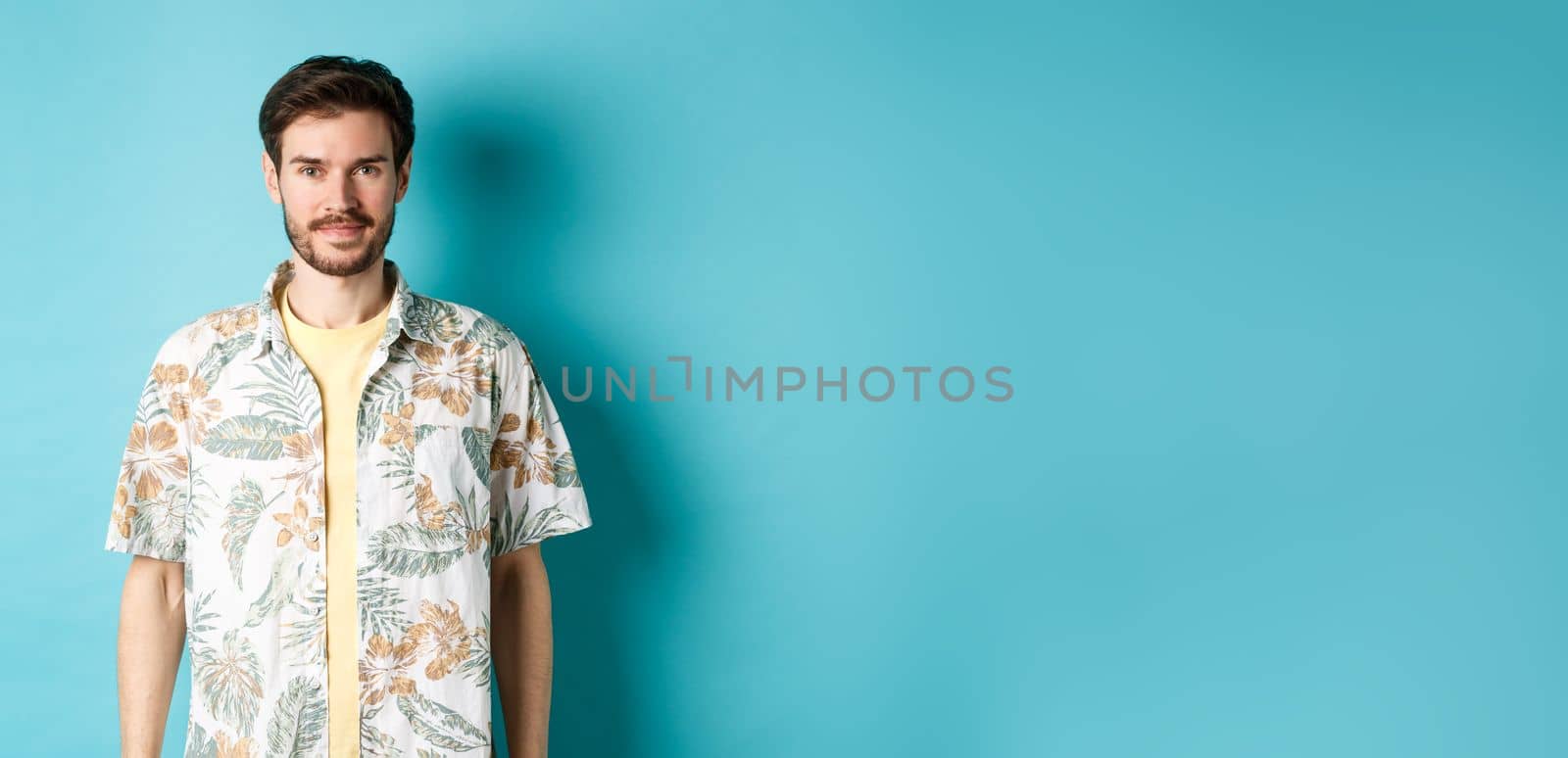 Happy handsome guy smiling, wearing hawaiian shirt on vacation. Concept of summer holiday.