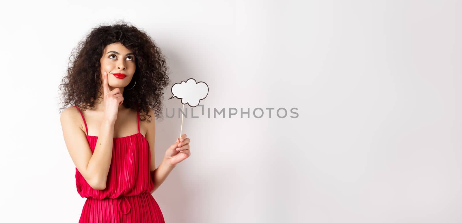 Thoughtful girl in red dress, holding small cloud and looking up with pleased smile, imaging things, standing over white background by Benzoix