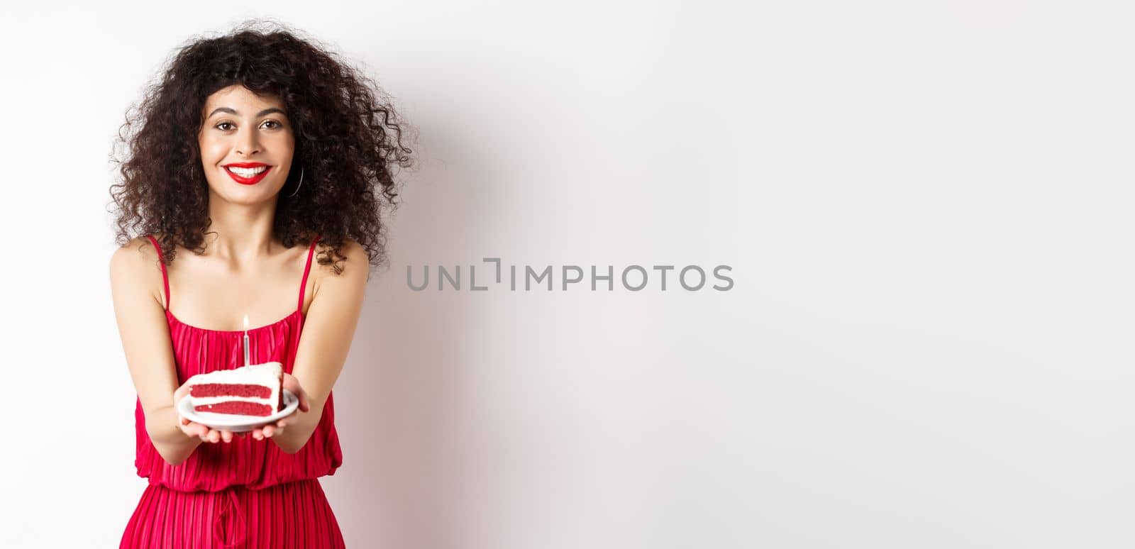 Beautiful woman congratulate with birthday, stretch out bday cake with candle and smiling, standing against white background.