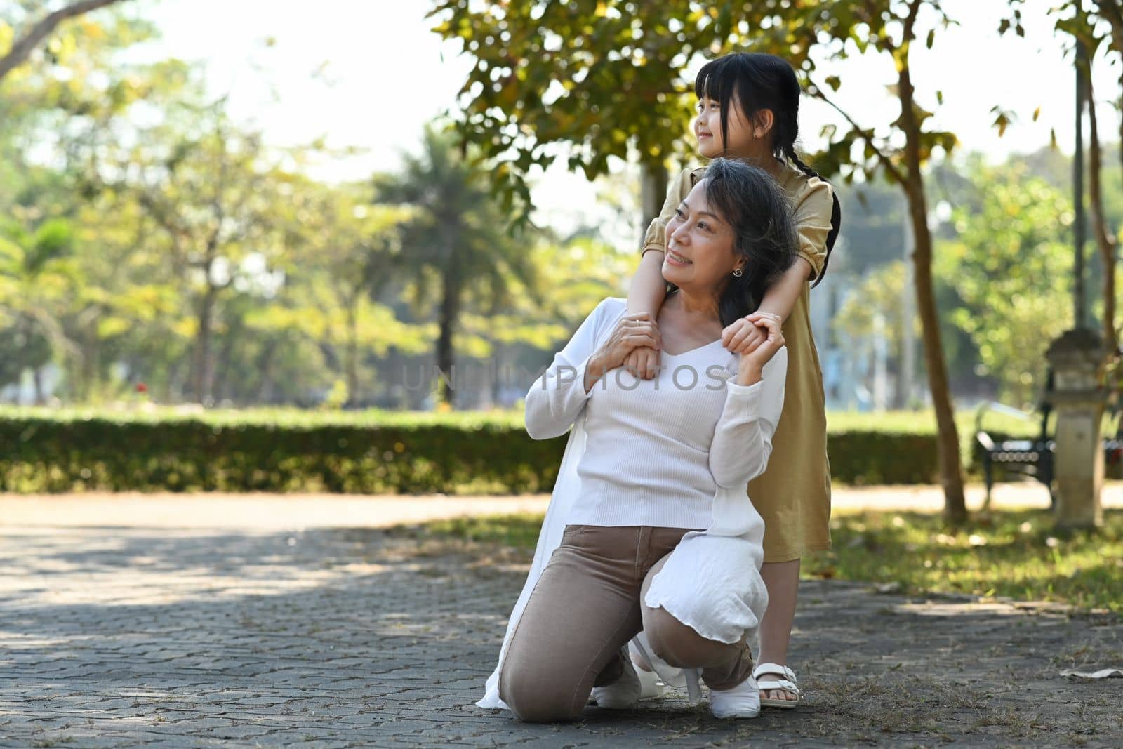 Image of happy mature woman and her cute grandchild enjoying leisure weekend time together outdoor by prathanchorruangsak