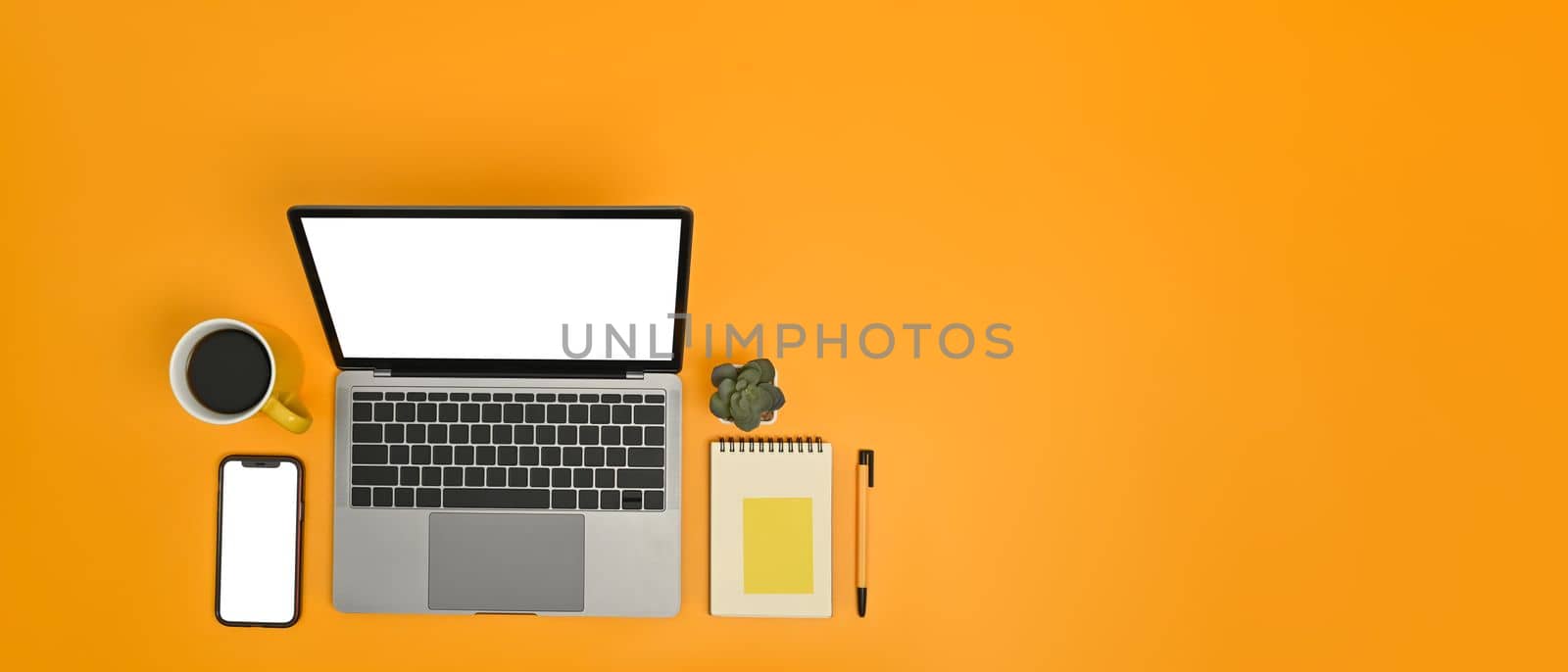 Horizontal image of laptop, smart phone notepad and coffee mug on yellow background. Copy space for text information.