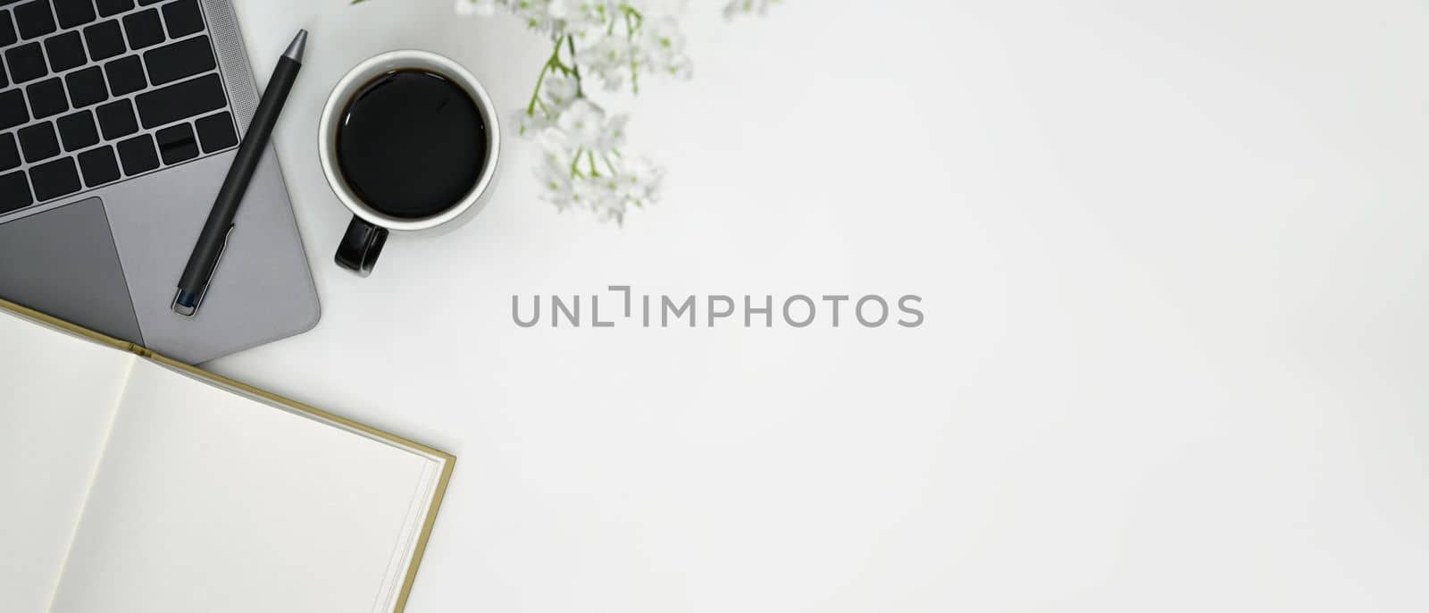 Flat lay cup of coffee, laptop and notebook on white office desk. Copy space for advertise text.