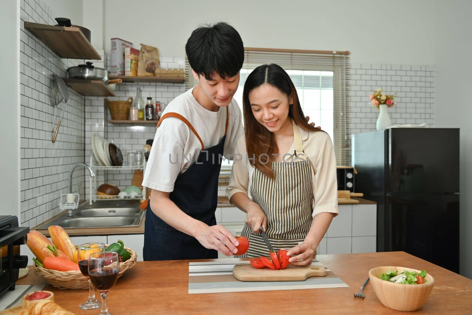 Shot of lovely young couple having fun in modern kitchen indoor while preparing vegetarian meal together by prathanchorruangsak