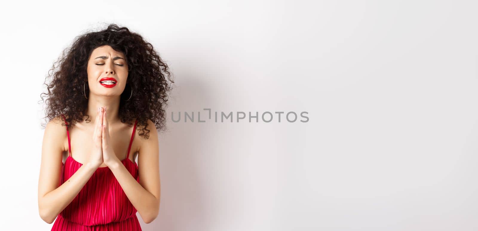 Desperate young woman in red dress begging for help, pleading and looking miserable, supplicating over white background by Benzoix