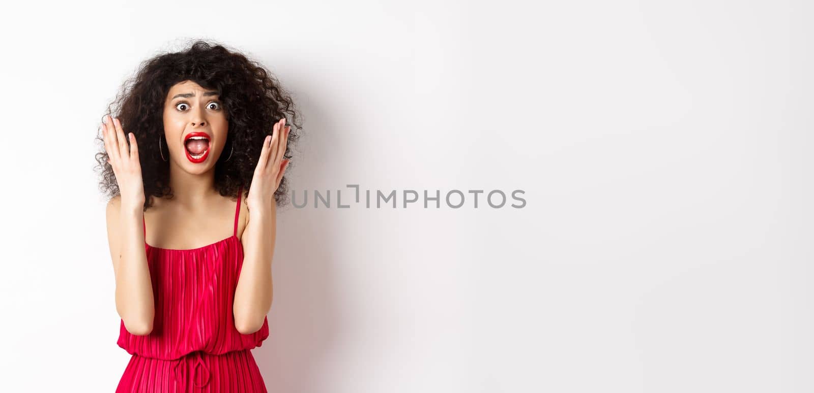 Woman scream in panic, wearing red dress and shouting at camera with anxious face, standing over white background by Benzoix