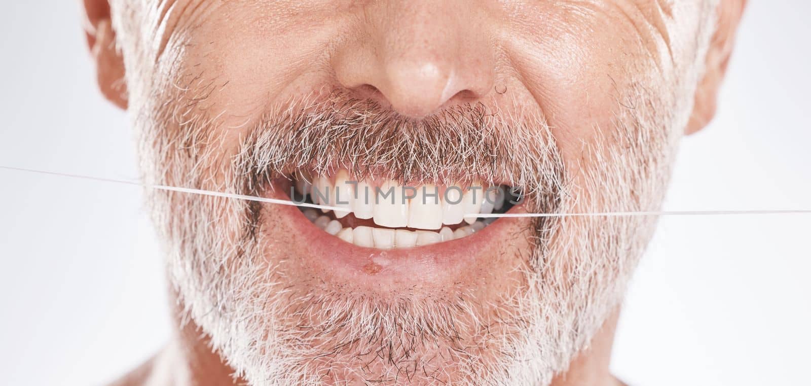 Dental, floss and mouth of senior man in studio isolated on a gray background. Hygiene, cleaning and elderly male model with product flossing teeth for oral wellness, tooth care and healthy gums. by YuriArcurs