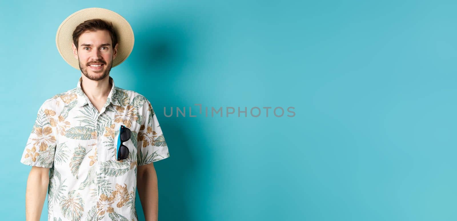 Happy and positive tourist in hawaiian shirt and straw hat, smiling at camera. Concept of tourism and summer holiday by Benzoix