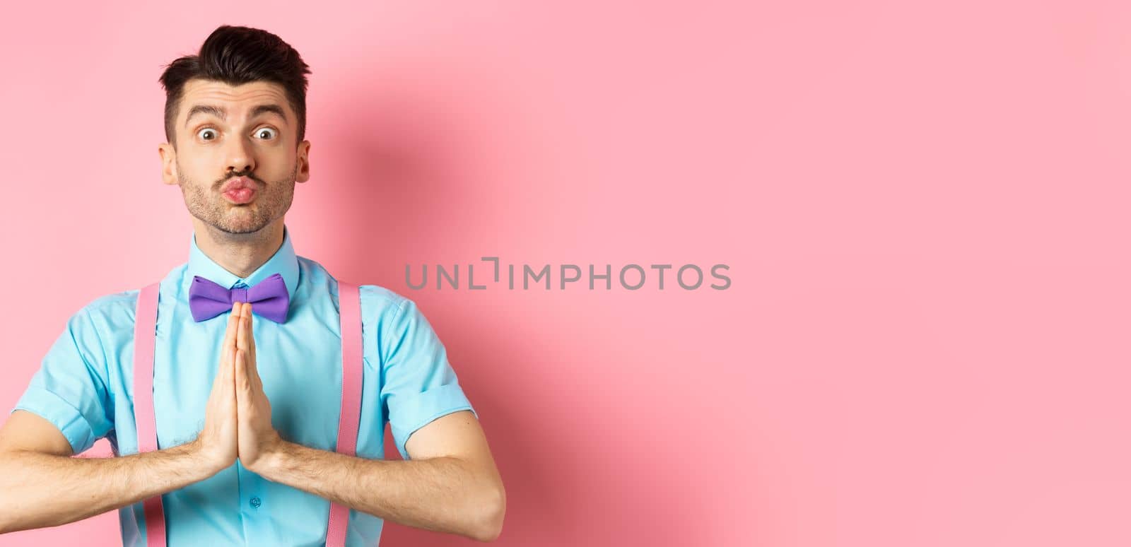 Young guy with cute face pucker lips and asking please, begging for favour, need something and lookin gpleading at camera, standing over pink background by Benzoix