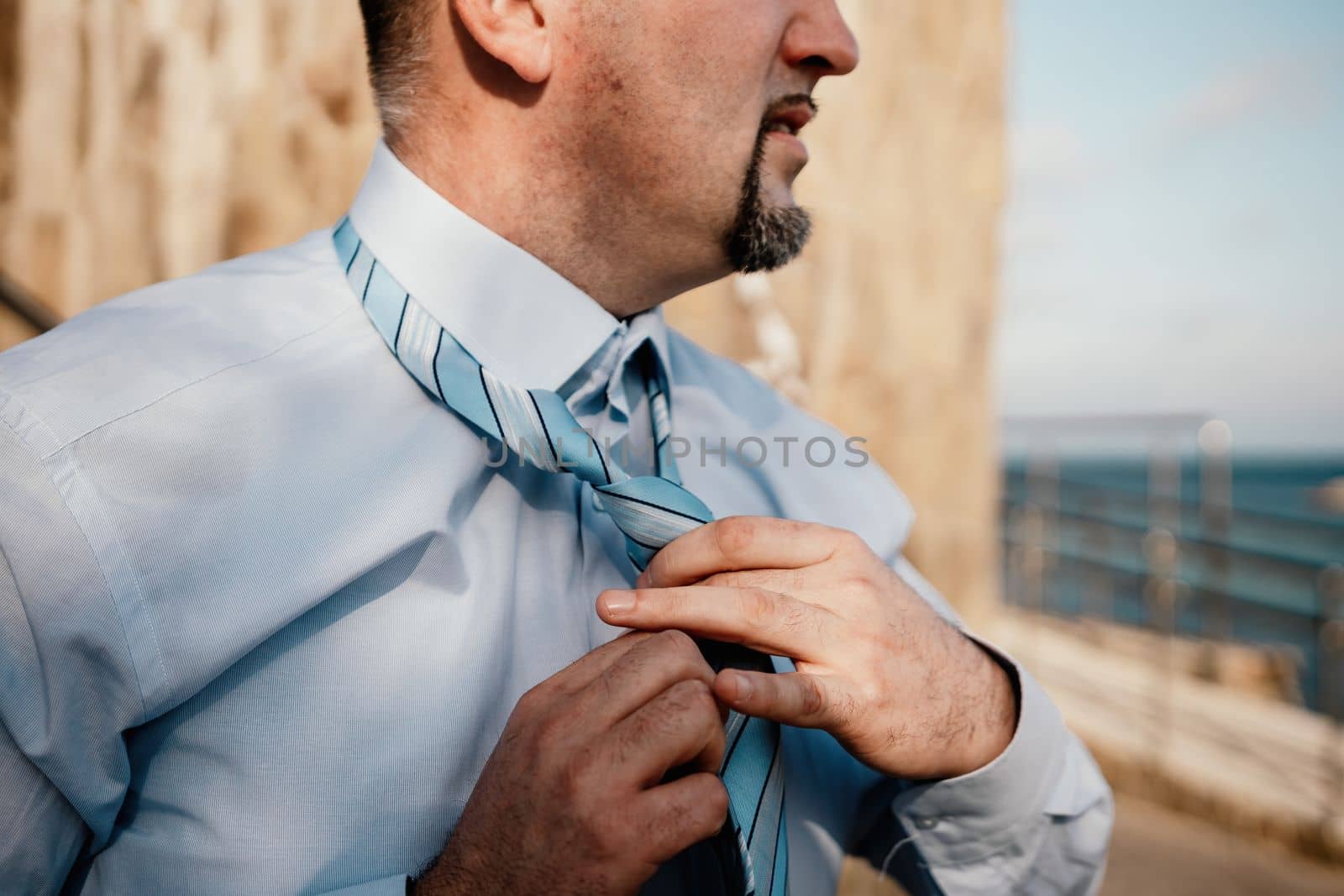 Close up of Man Adjusting Tie of Suit. Businessman in white shirt straightens his tie, close-up.