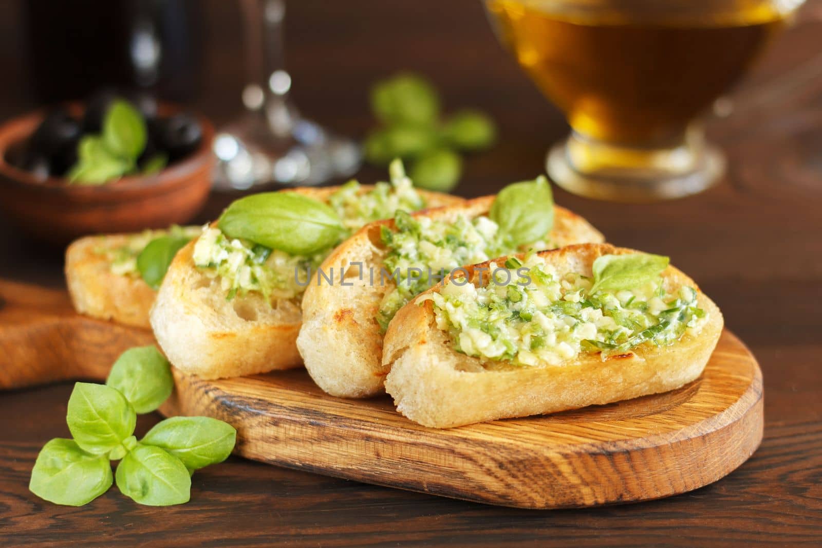 Delicious bread with garlic, cheese and herbs, red wine and olives on a wooden table.