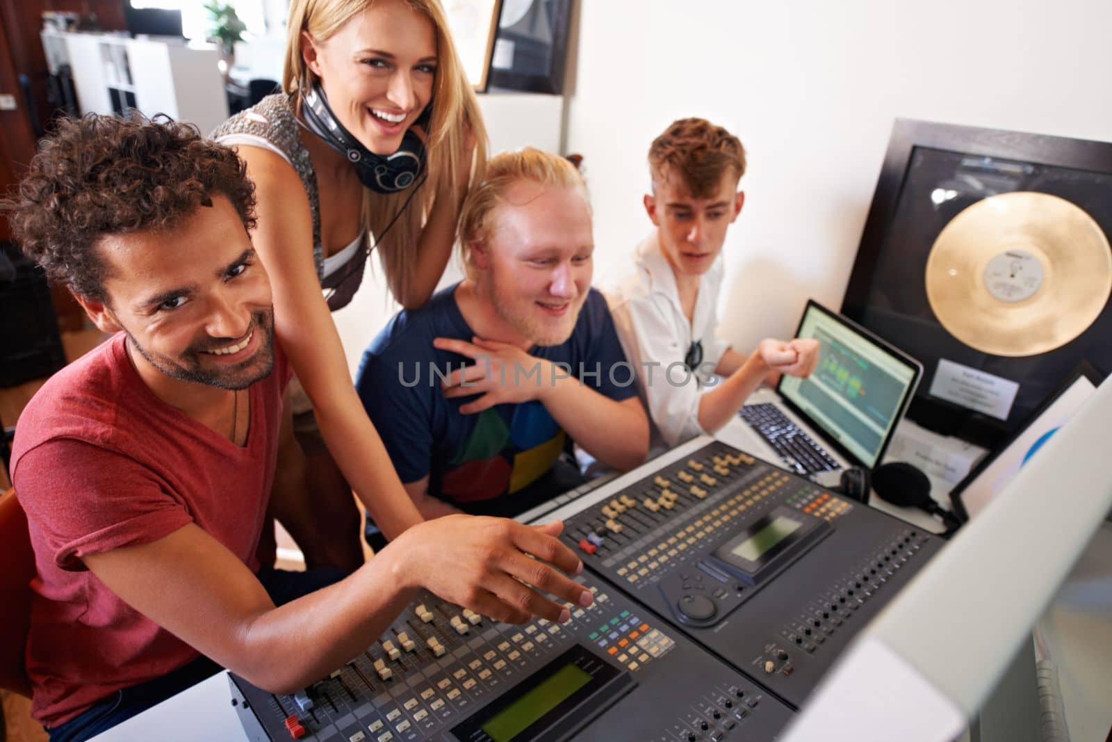Creating a hit takes time...Four young audio engineers working on a mixing desk