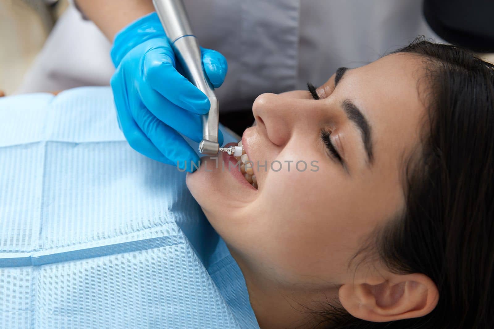 Young woman getting her teeth polished in dental clinic. Professional dental cleaning concept by Mariakray
