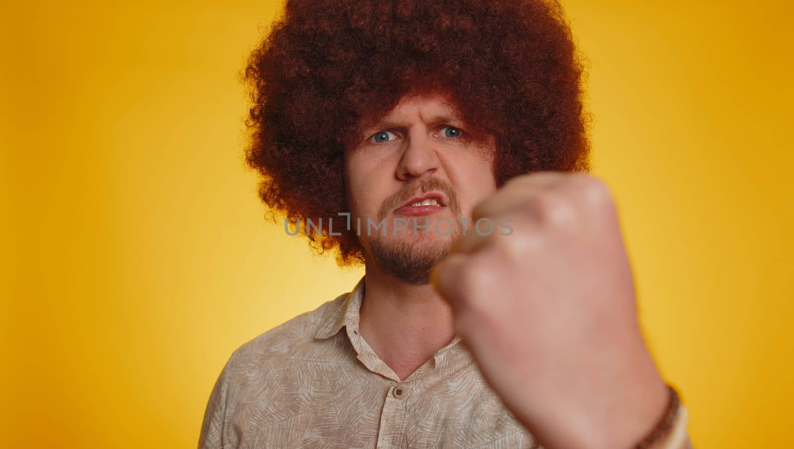 Quarrel. Displeased man with lush Afro hairstyle gesturing hands with irritation and displeasure, blaming scolding for failure, asking why this happened. Young hipster guy on yellow studio background