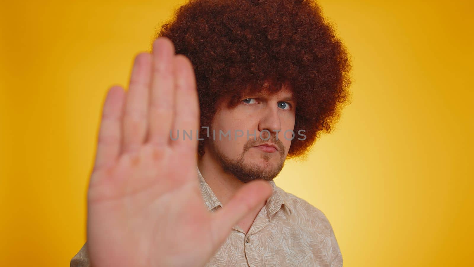 No stop. Serious man say No, hold palm folded crossed hands in stop danger gesture, warning of finish, prohibited access, declining communication, body language. Young hipster guy on yellow background