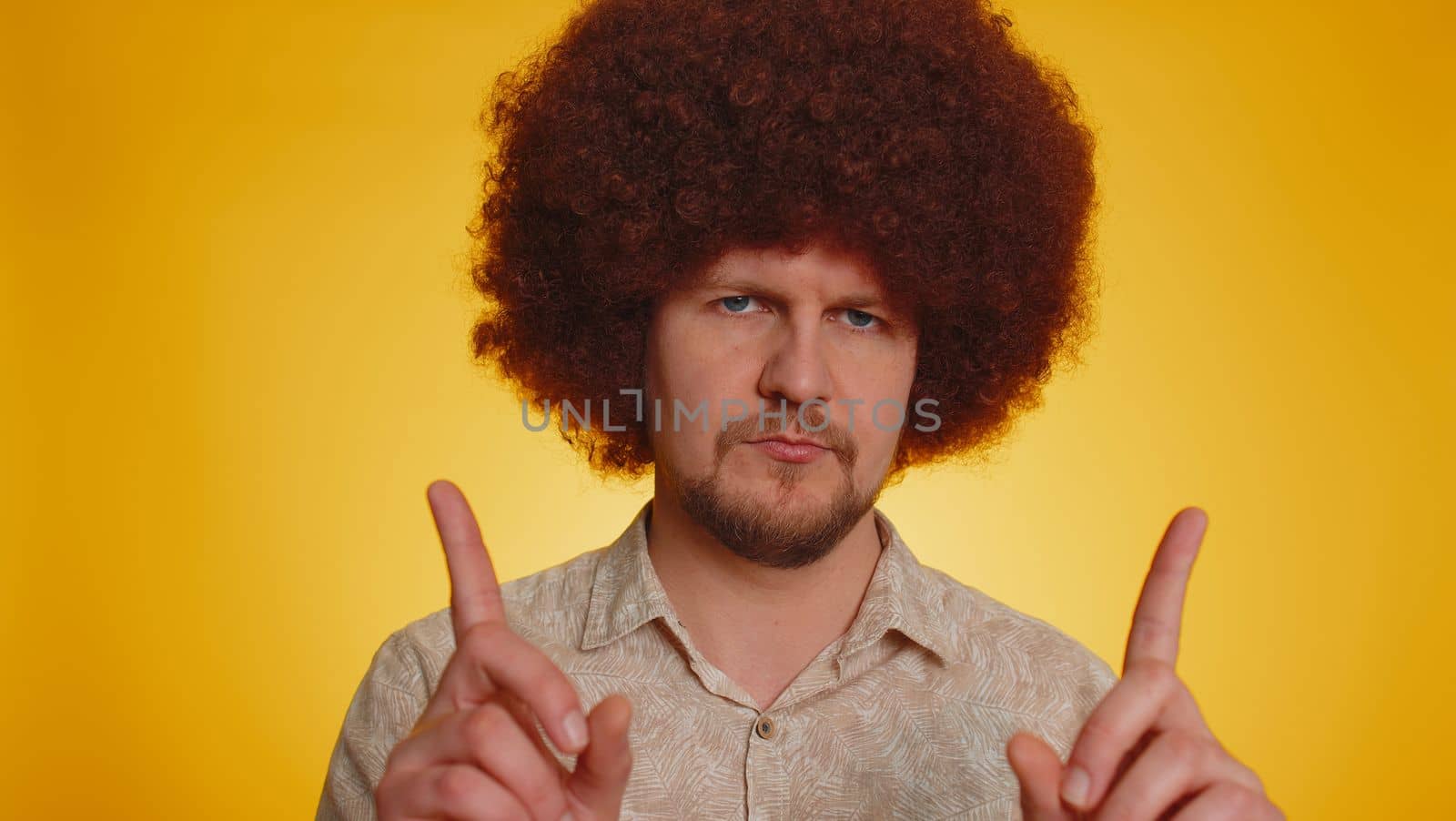 Displeased upset bearded man with afro hairstyle reacting to unpleasant awful idea, dissatisfied with bad quality, wave hand, shake head No, dismiss idea, dont like proposal. Guy on yellow background