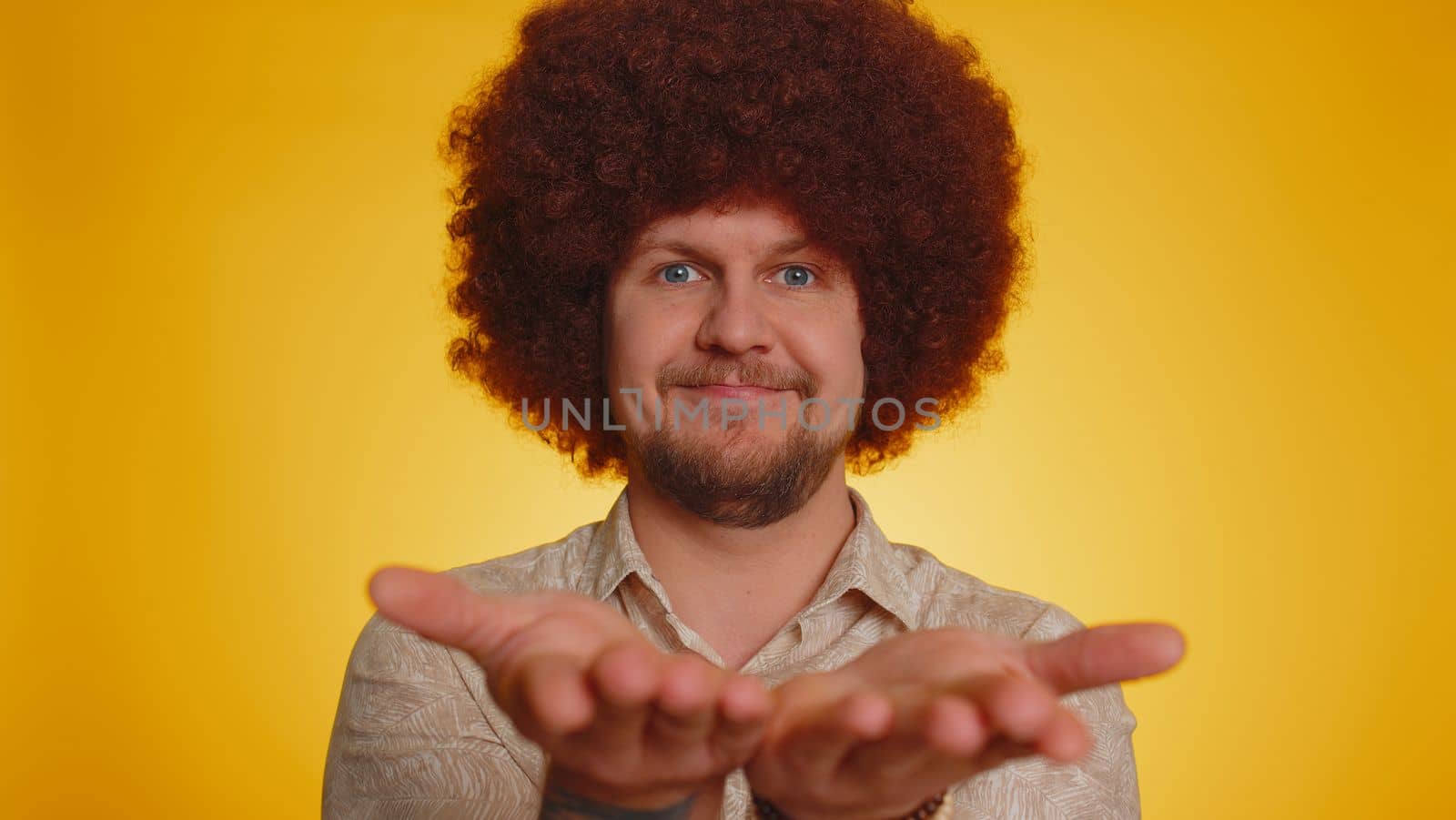 Free gifts and presents for you. Man with afro hairstyle coiffure opening hands, glad to see, excitement, preparing surprise, sharing love emotions, congratulating. Hipster guy on yellow background