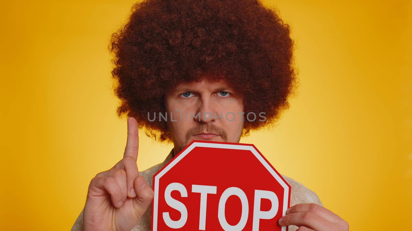No stop. Serious man say No, hold inscription text red No stop danger sign, warning of finish, prohibited access declining communication, body language, trouble, protest. Guy on yellow background
