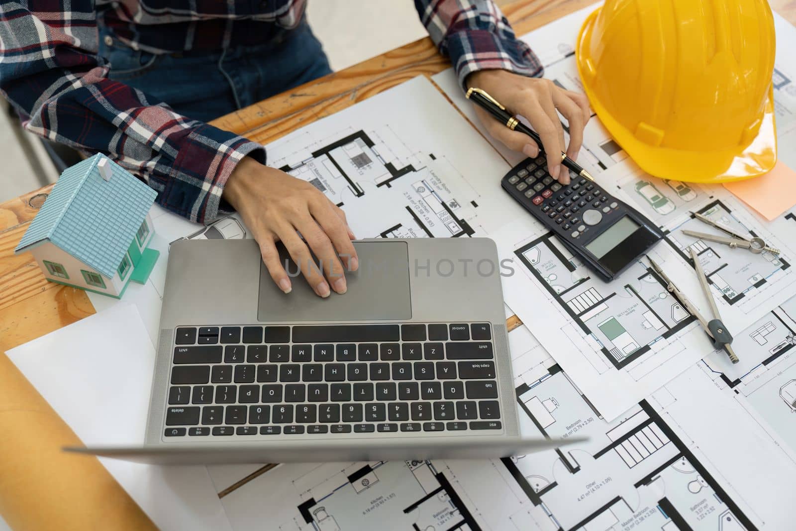 Close up Architect or Engineer using on calculator for calculating value estimating for safety with the drawing construction building.