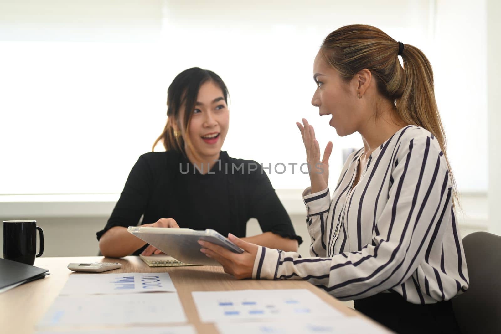 Young woman office worker telling gossips, enjoy friendly conversation with her colleague.