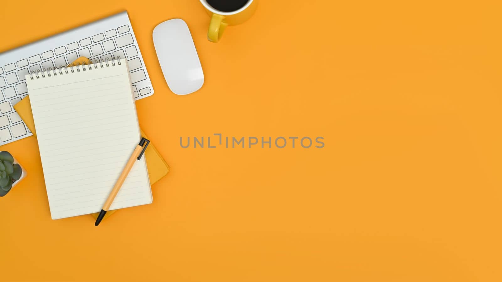 Top view of notepad, keyboard, mouse and coffee cup on yellow background. Copy space for your text by prathanchorruangsak