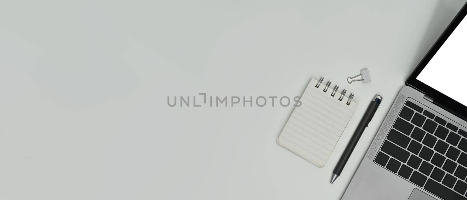 Empty notepad, pen and laptop computer on white background. Top view with copy space.