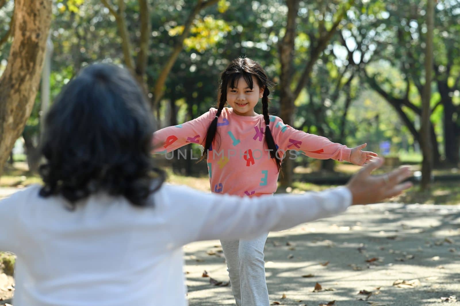 Affectionate little girl running to hug grandmother with arms open. Happy moment, family and love concept.