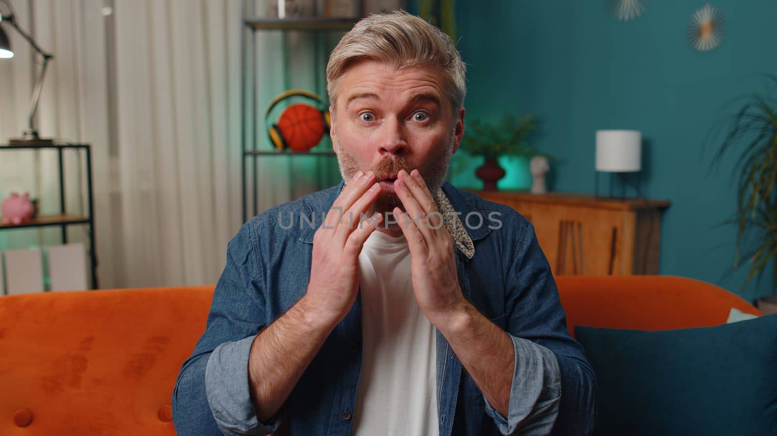 Oh my God, Wow. Surprised middle-aged senior man at home couch, shocked by sudden victory triumph, good win news, celebrating lottery jackpot luck. Excited amazed mature old guy in night evening room