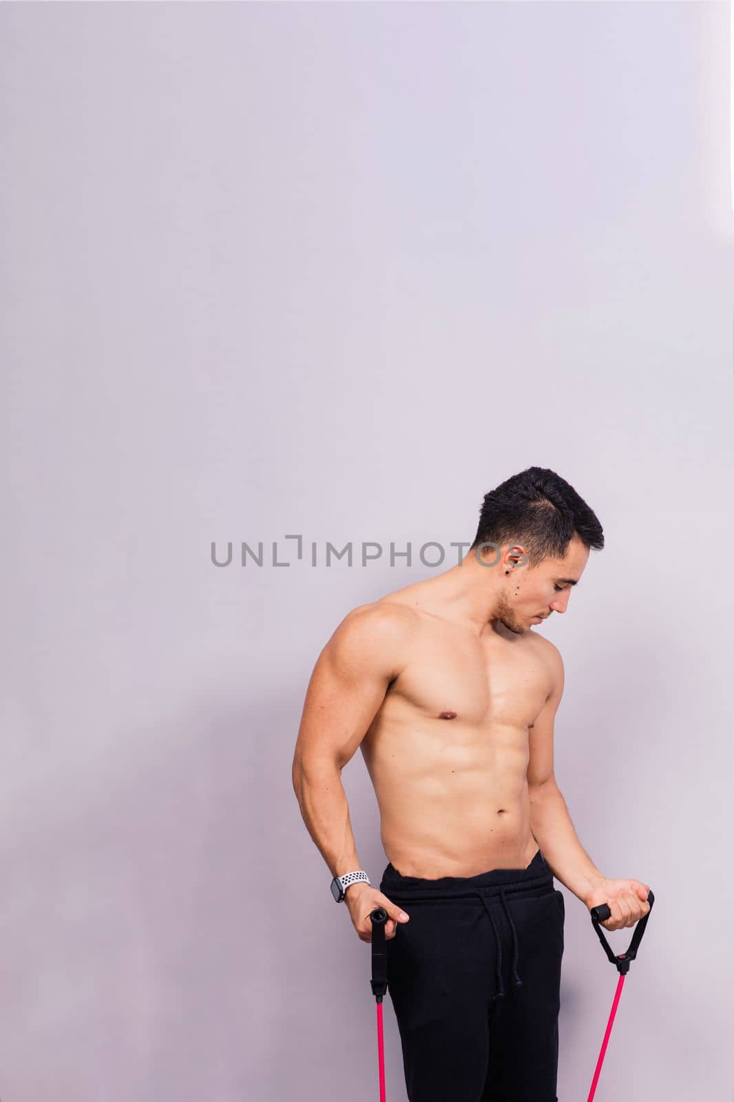 Athletic man skipping with a jump rope on grey background. Best cardio workout by Zelenin