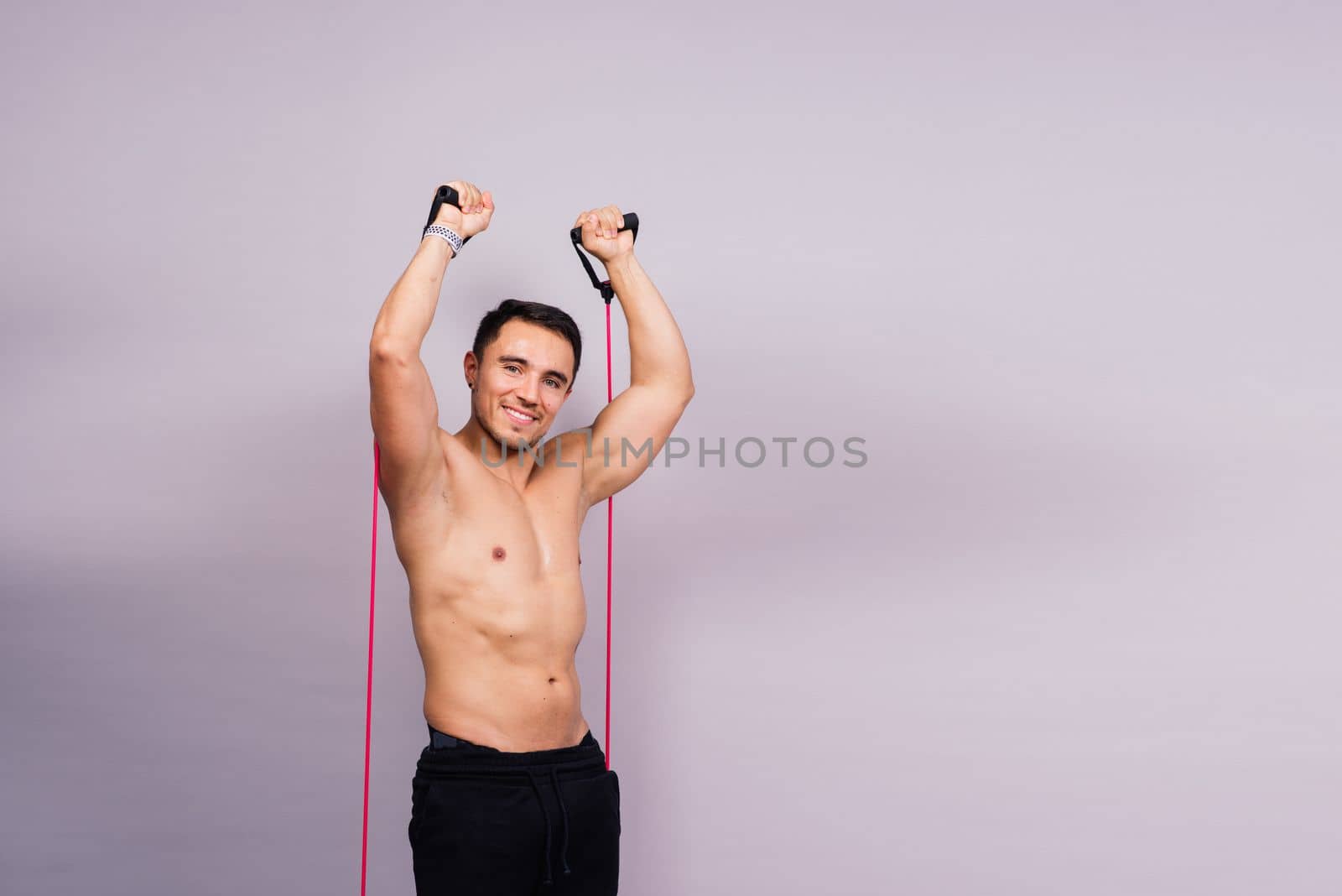 Athletic man skipping with jump rope on grey background. Best cardio workout