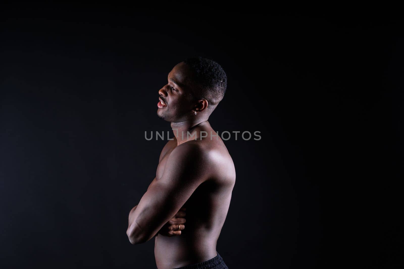 Portrait of athletic african american man topless, black background