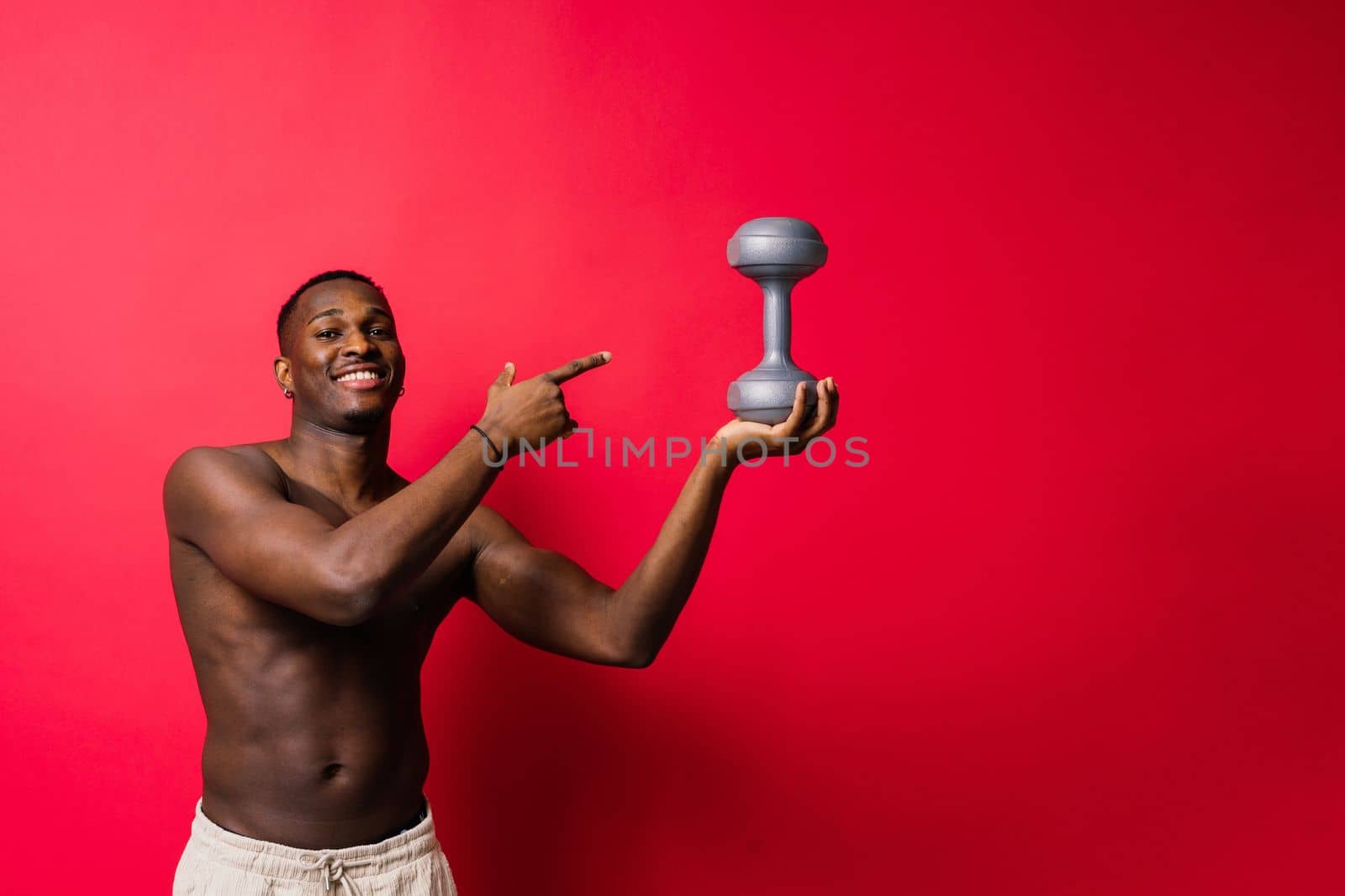 Portrait of a happy african man with dumbbells over red background by Zelenin