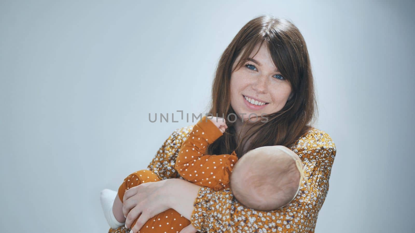 A loving mother sings for her child against a gray background