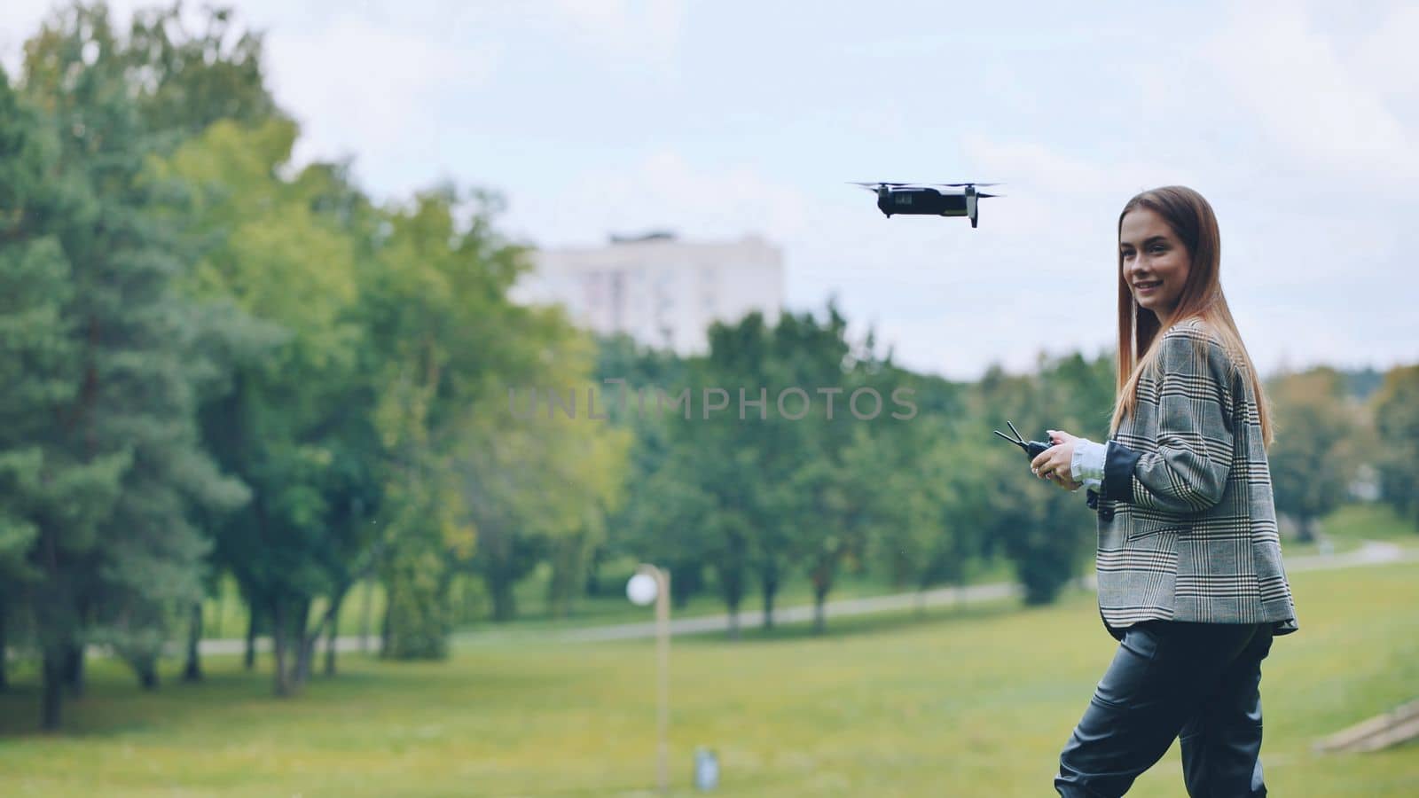 A cute girl controls a drone in the park