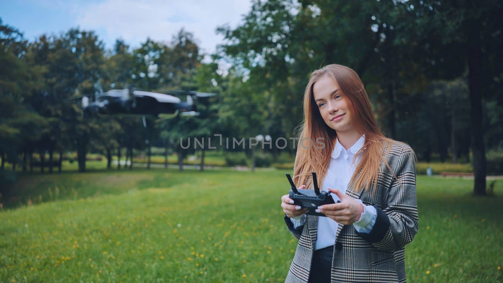 A cute girl controls a drone in the park