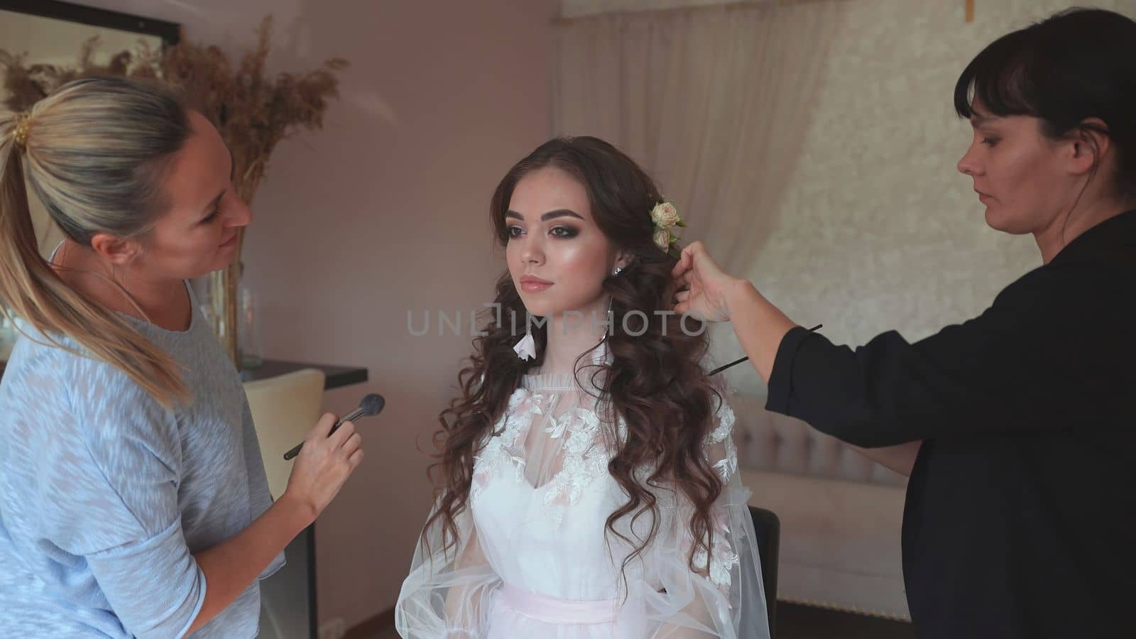 Makeup artist and hairdresser work on the image of the model. by DovidPro