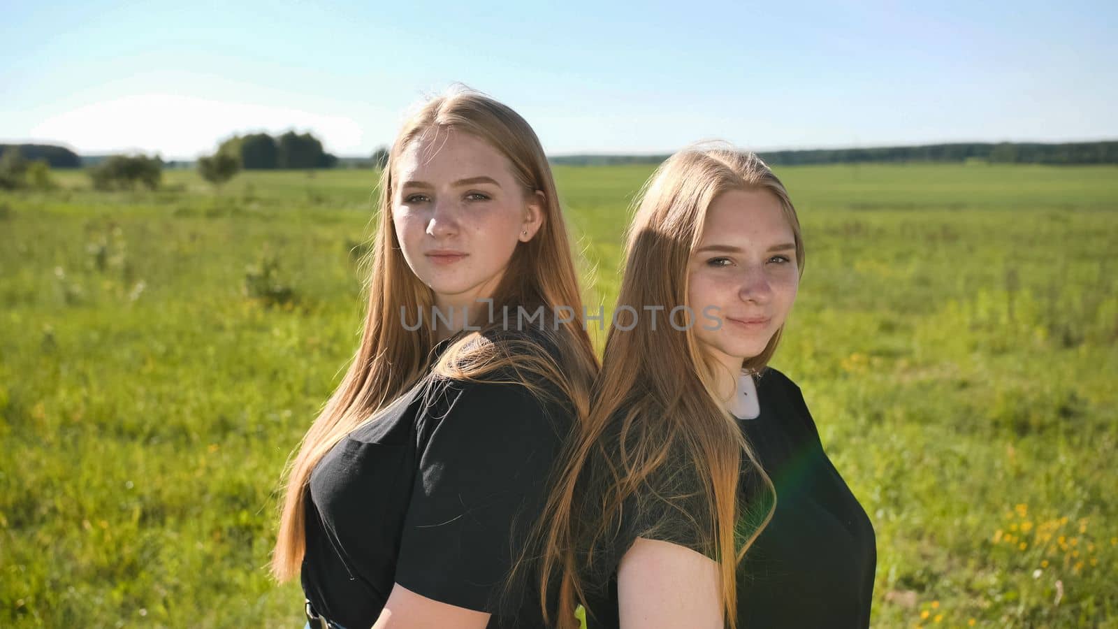 Portrait of two twin sisters in the field on a warm summer day.