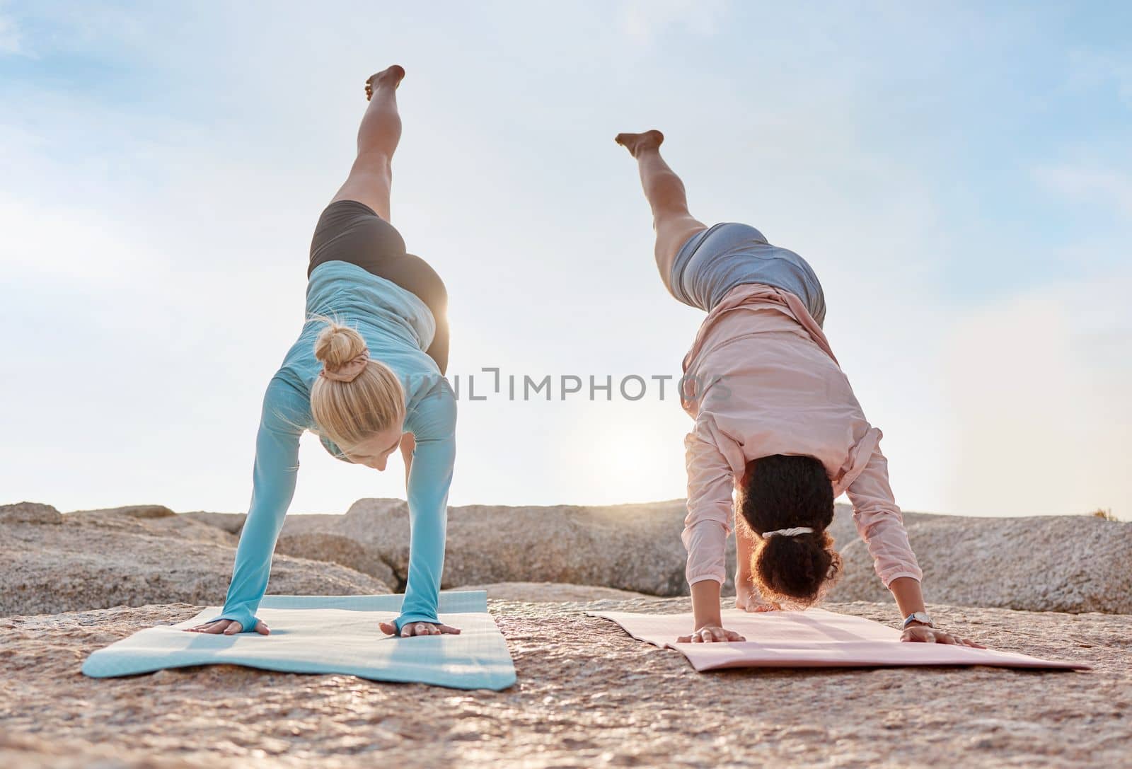 Yoga, stretching and fitness with friends on the beach together for mental health or wellness in summer. Exercise, diversity or nature with a woman yogi and friend outside for inner peace or balance by YuriArcurs