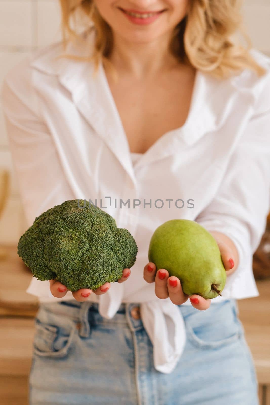 The girl holds a pear and broccoli in her hands. The hostess holds vegetables and fruits in her hands.