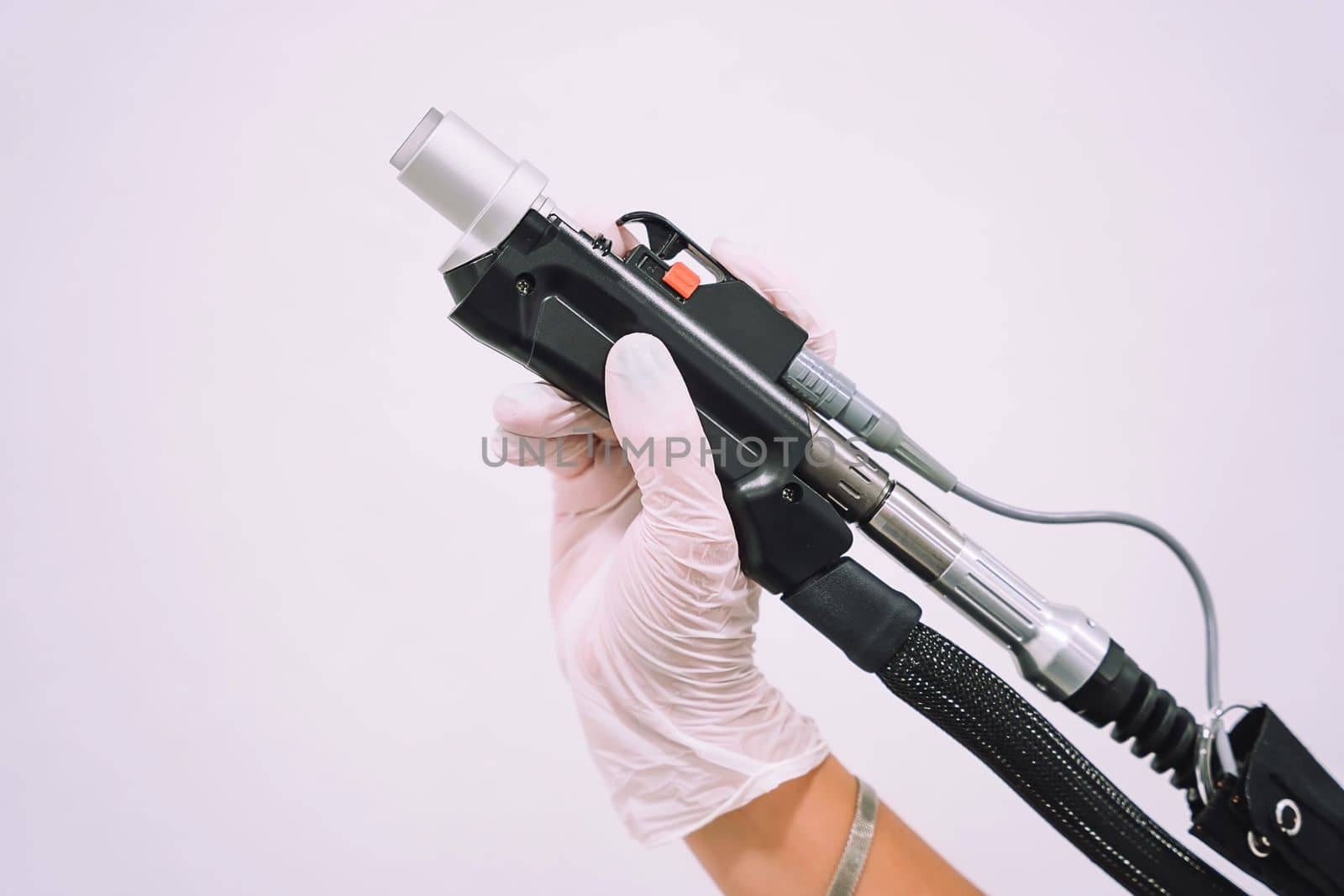 Close up shot of gloved hand with the laser hair removal machine's handpiece. Alexandrite laser techhnology removing hair. Beauty technology concept
