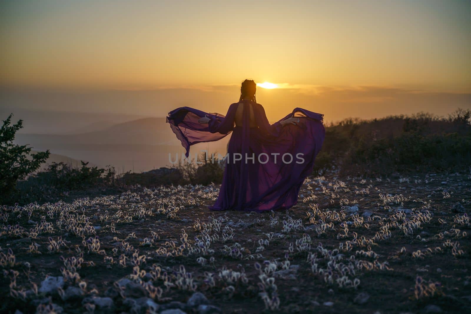 Sunset purple dress woman mountains. Rise of the mystic. sunset over the clouds with a girl in a long purple dress. In the meadow there is a grass dream with purple flowers. by Matiunina