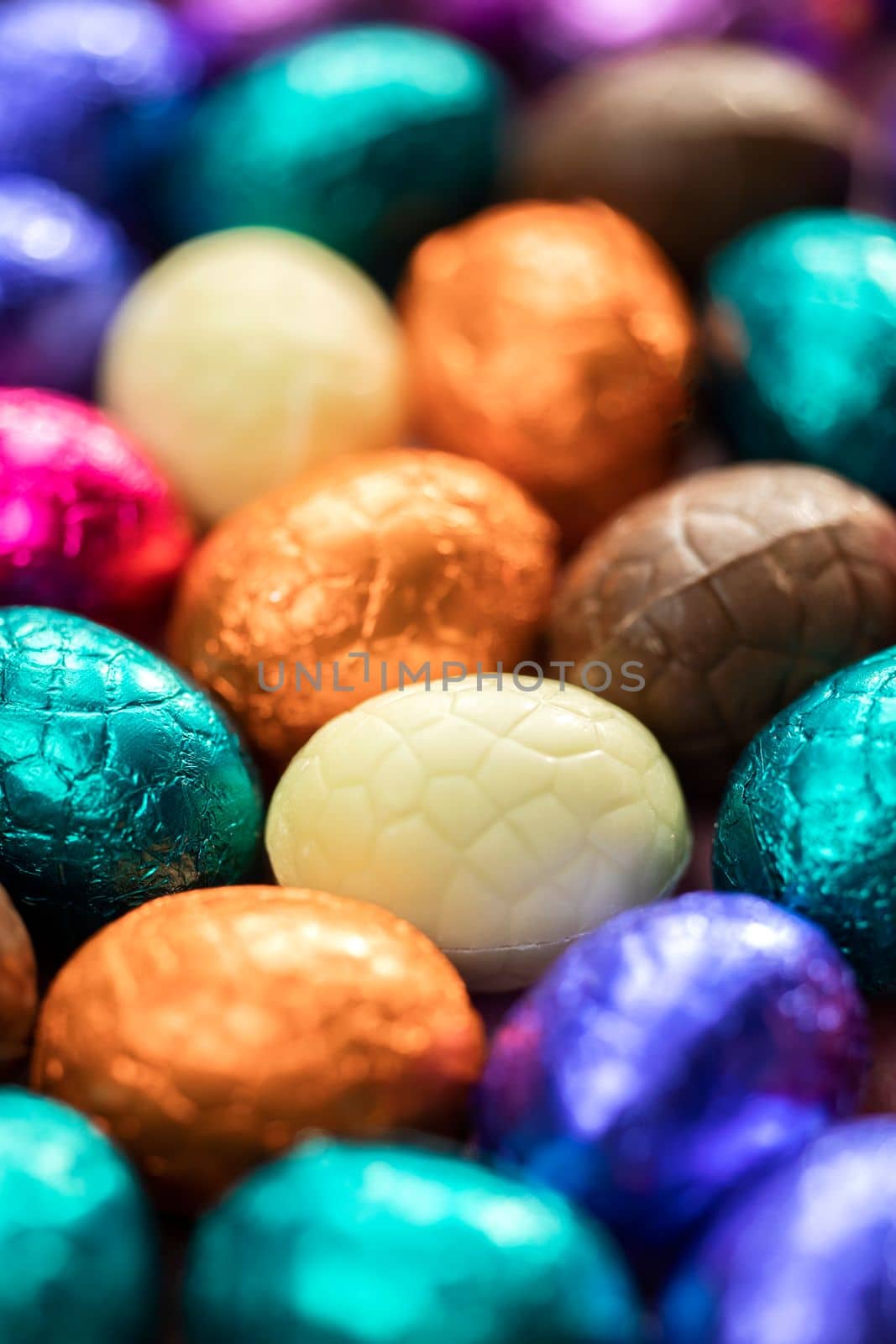 Big pile of colorful wrapped chocolate easter eggs, shiny festive Easter concept, Happy easter close-up candy sweets concept macro various colors