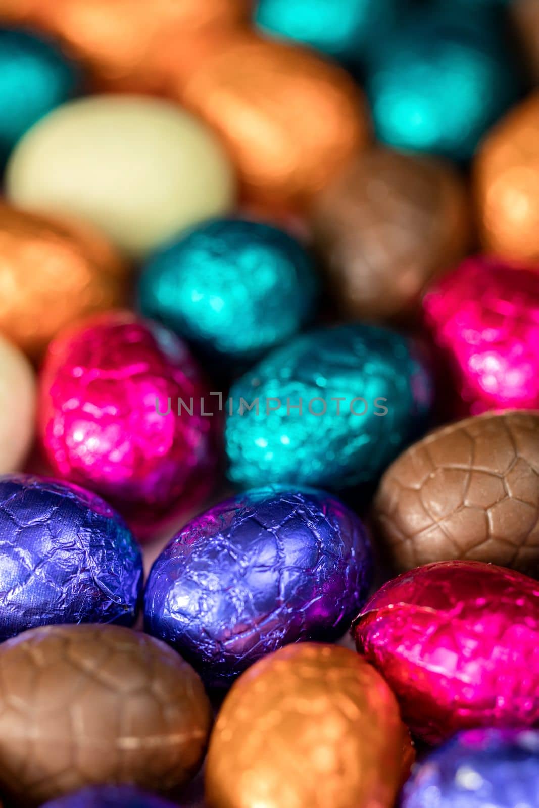 Big pile of colorful wrapped chocolate easter eggs, shiny festive Easter concept, Happy easter close-up candy sweets concept macro various colors