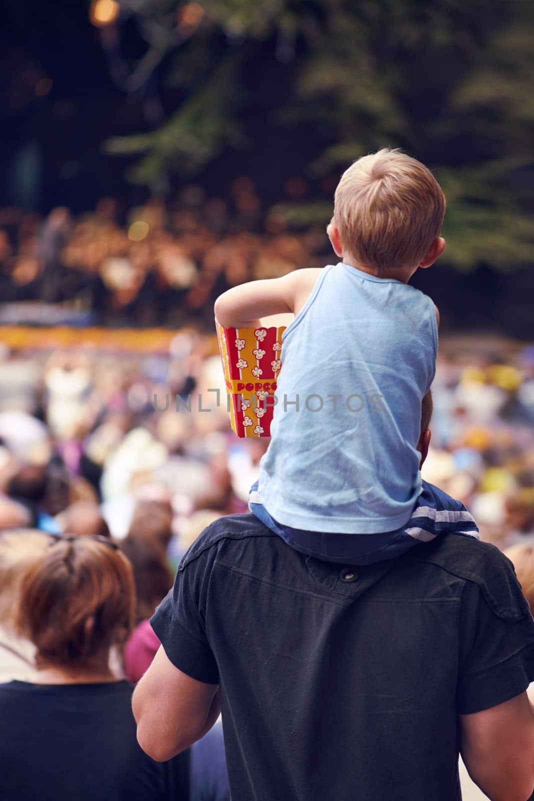 Beats and eats. Rearview shot of a young boy sitting on his fathers shoulders at an outdoor festival