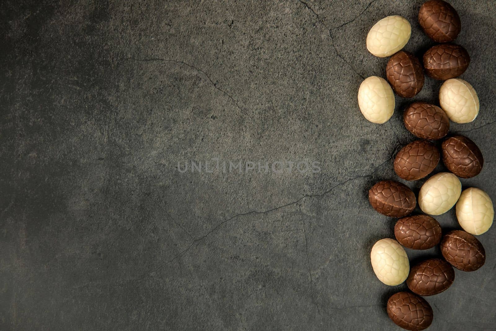 Composition with chocolate Easter eggs on dark background copy space top view. Happy Easter holiday concept sweets