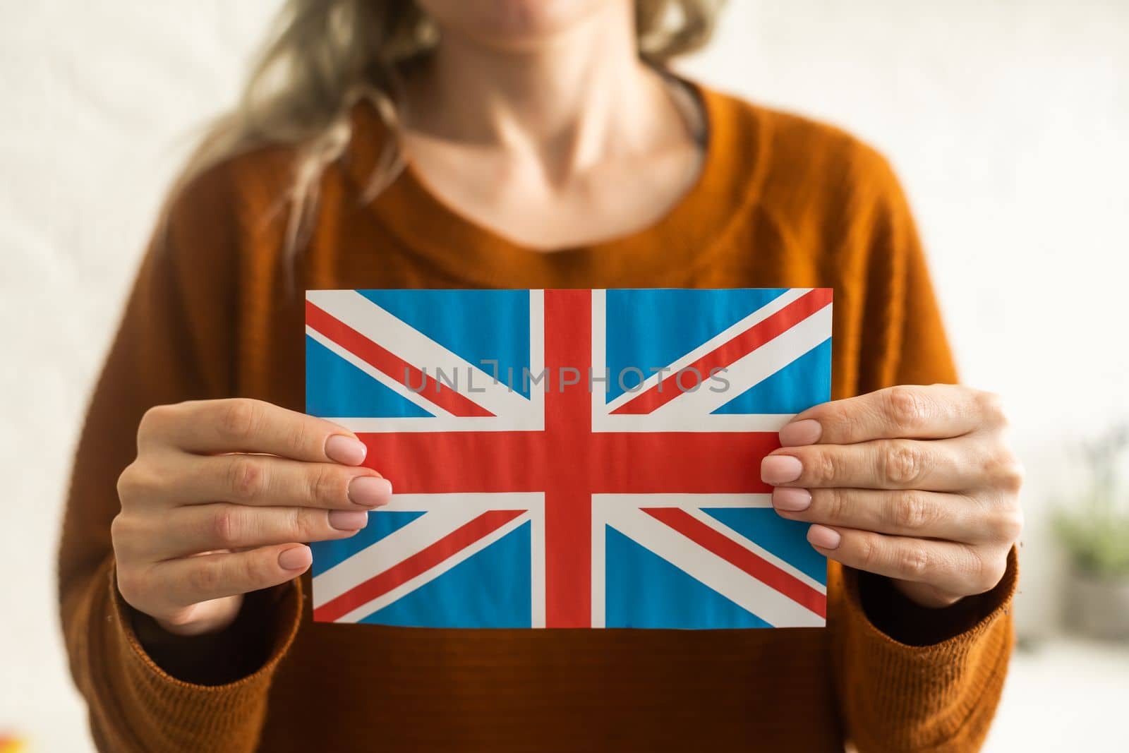 Hand holding flag of UK, isolated on white background by Andelov13